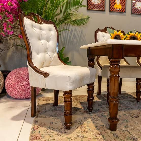 Turned wooden dining table leg and tufted chair joinery close-up